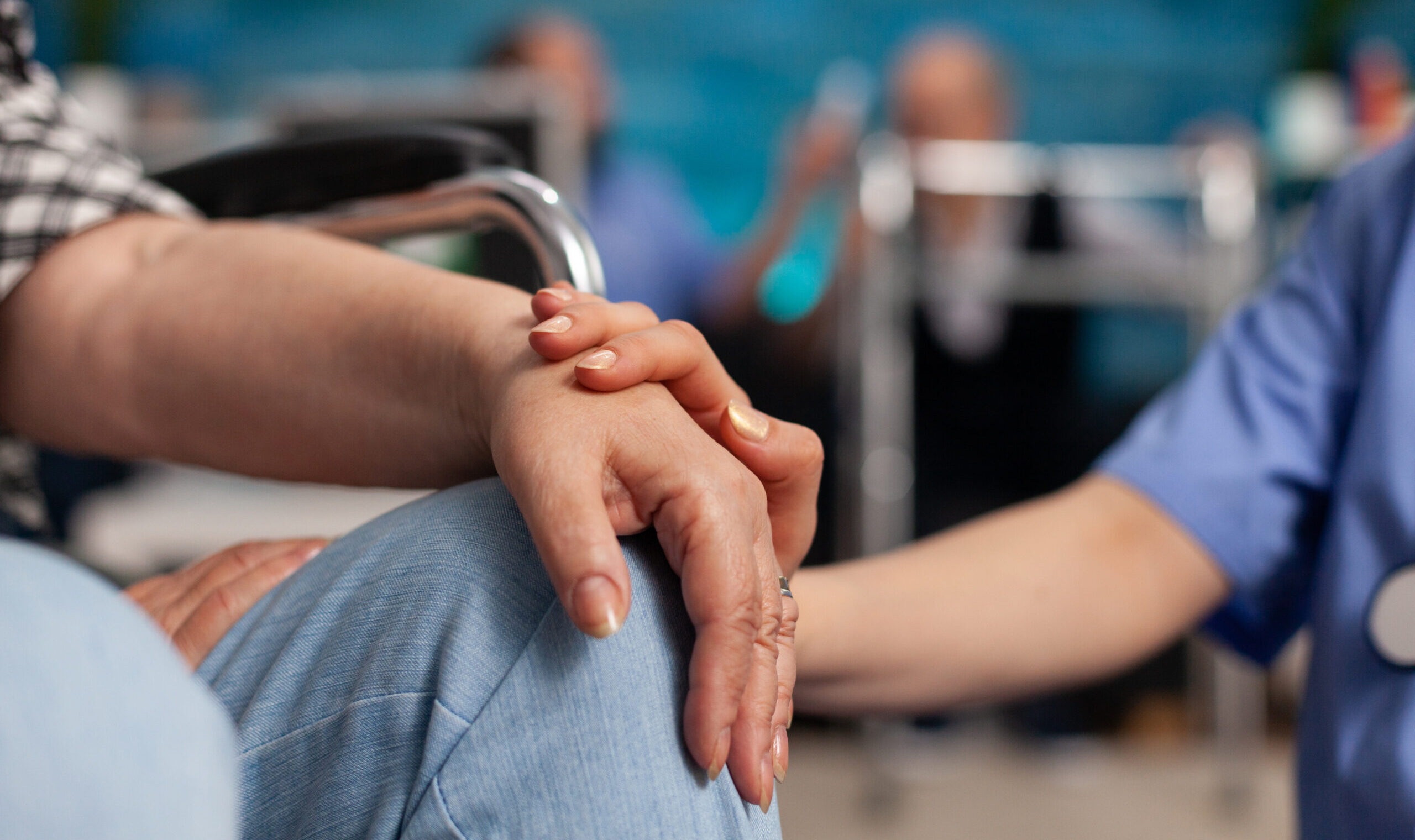 Social assistant worker consoling handicapped pensioner patient touching hands