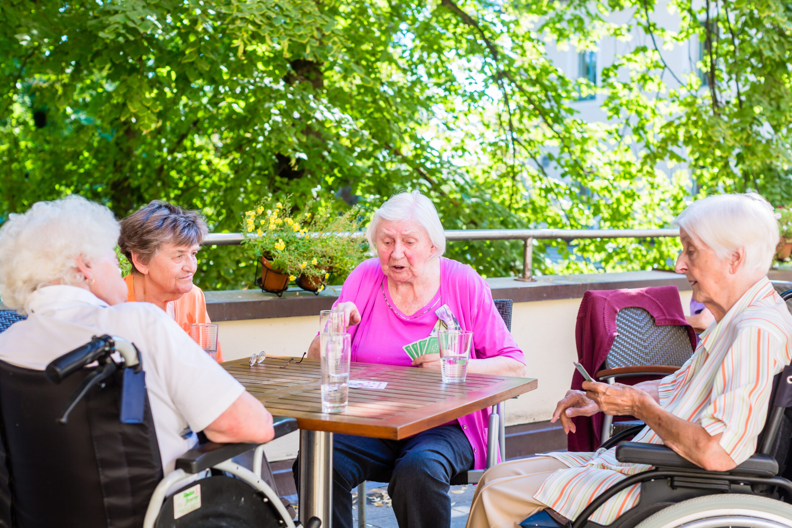 Group of seniors playing board game on terrace of retirement home