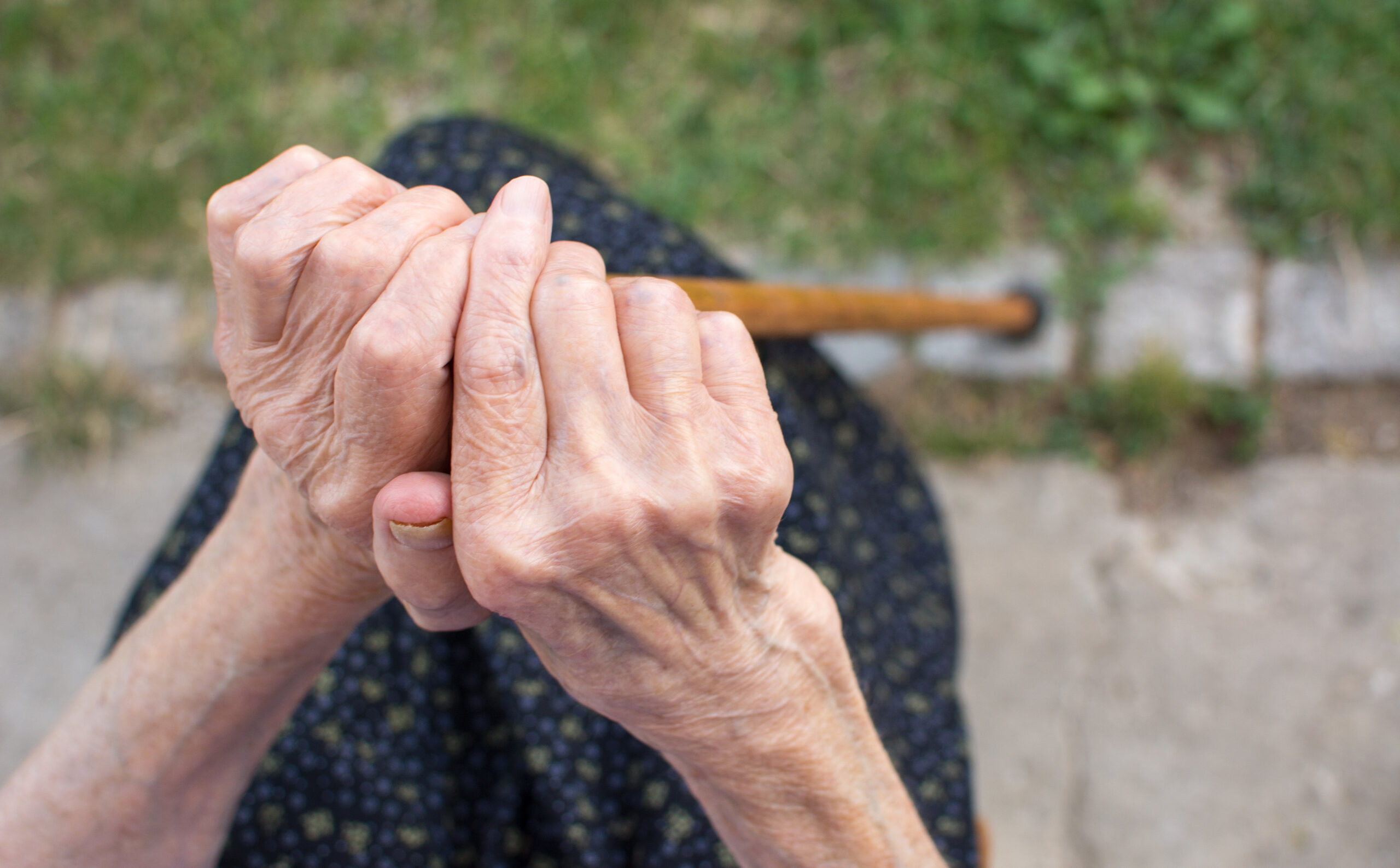 Old woman hands holding a walking cane